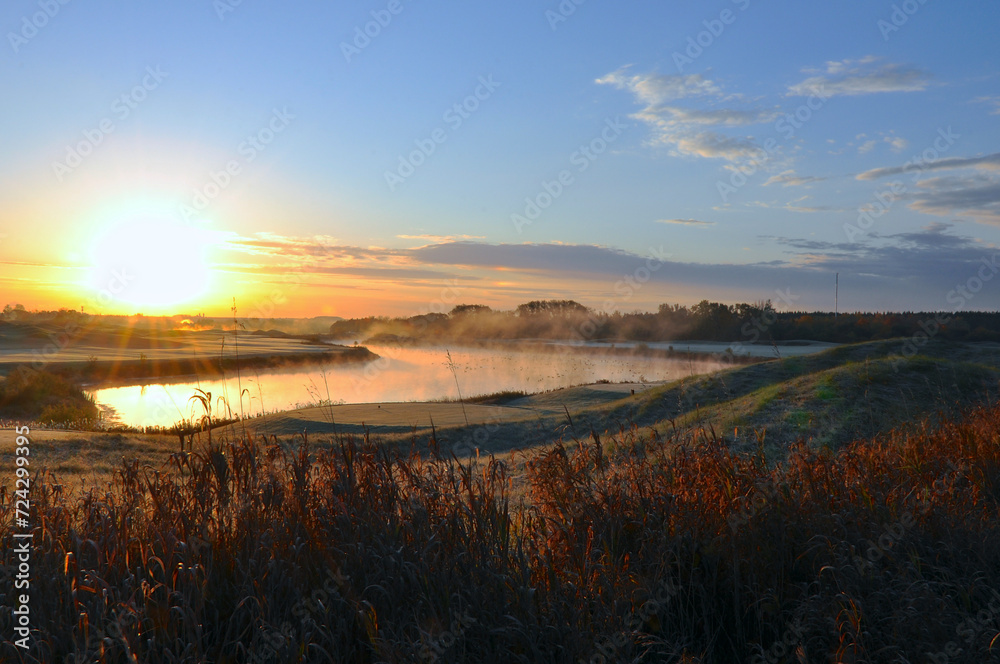 Sunrise in the golf course with mist and birds
