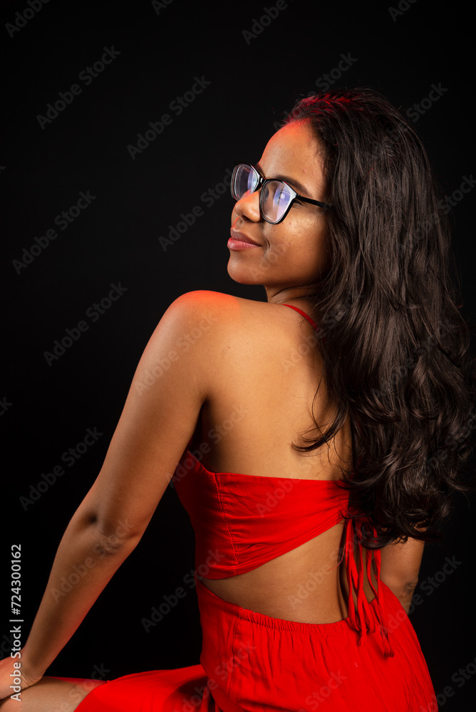 Portrait of beautiful young woman wearing glasses and in red dress sitting posing for photo. Portrait of beautiful young woman wearing glasses and in red dress sitting posing for photo.