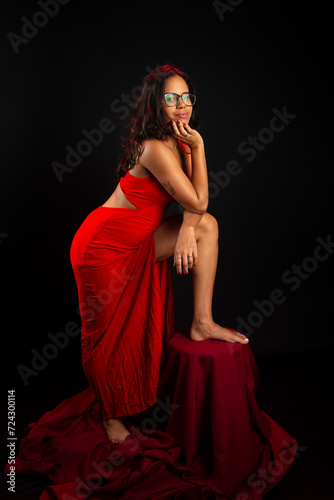 Beautiful young woman dressed in red with her foot on a chair posing for the photo.