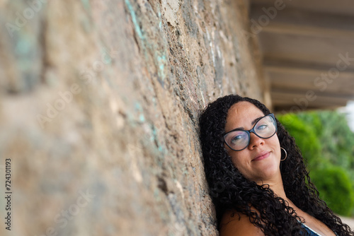 Beautiful, curly-haired woman wearing prescription glasses looking and smiling at the camera.