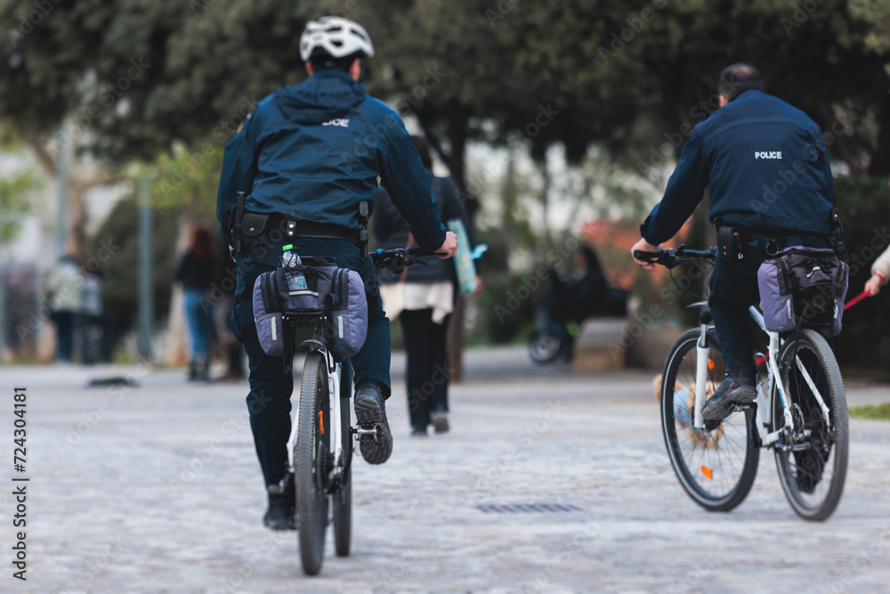 Fototapeta premium Police squad formation on duty riding bike and bicycle, maintain public order in the european city streets, group of policemen patrol on bycicles with 