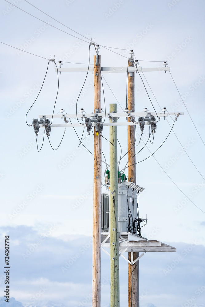 Wooden power poles standing tall against a blue sky with transformers and power lines in Rural Alberta Canada. Wooden power poles standing tall against a blue sky with transformers and power lines in Rural Alberta Canada.