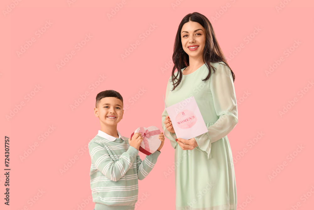 Cute little boy greeting his mother with International Women's day on pink background Cute little boy greeting his mother with International Women's day on pink background