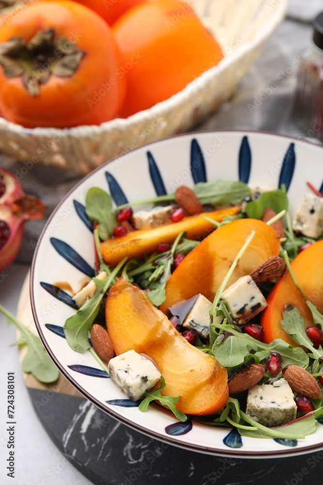 Tasty salad with persimmon, blue cheese, pomegranate and almonds served on white table, closeup Tasty salad with persimmon, blue cheese, pomegranate and almonds served on white table, closeup