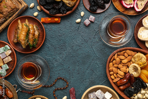 Frame made of traditional Eastern sweets and tea for Ramadan on dark color background © Pixel-Shot