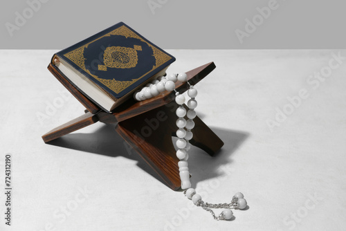 Rehal with Koran and prayer beads for Ramadan on white table photo