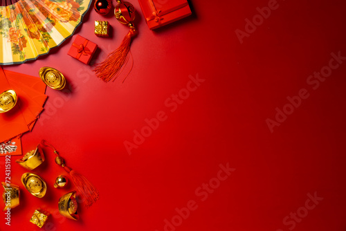 Chinese New Year ambiance through this top-view arrangement featuring fans, Feng Shui items, symbolic coins, sycee on red setting, ready for text or advertising, card Chinese 