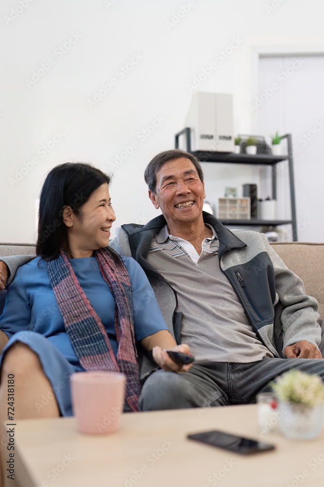 Asian senior couple enjoying in their favorite TV. Happy retirement couple watching television together in living room Asian senior couple enjoying in their favorite TV. Happy retirement couple watching television together in living room