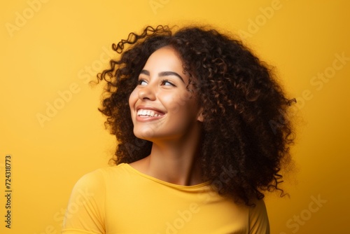 Portrait of happy african american woman with curly hair over yellow background