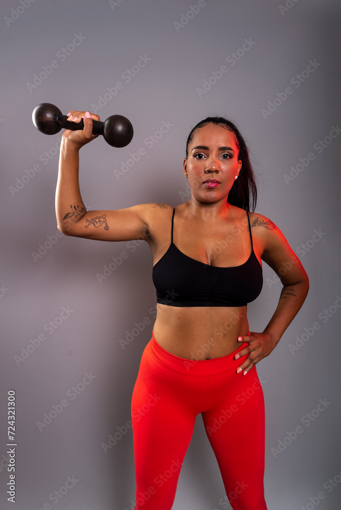 Beautiful brunette woman, in gym clothes, holding black dumbbells at head height. Healthy life. Beautiful brunette woman, in gym clothes, holding black dumbbells at head height. Healthy life.