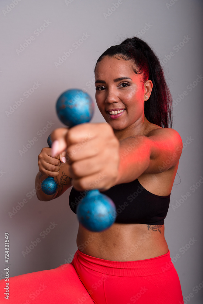 Beautiful, brunette, happy and smiling woman in gym clothes, holding dumbbells and looking at the camera. Healthy life. Beautiful, brunette, happy and smiling woman in gym clothes, holding dumbbells and looking at the camera. Healthy life.