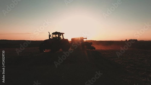 a tractor pulling a planter at sunset