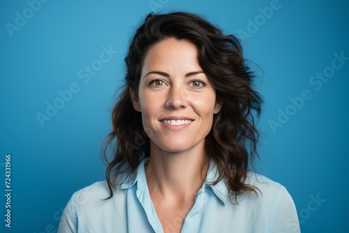 Portrait of a smiling businesswoman in blue shirt on blue background