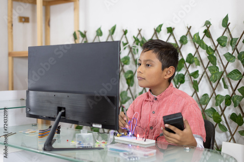 Latino boy taking virtual class about electronics, looking at the screen