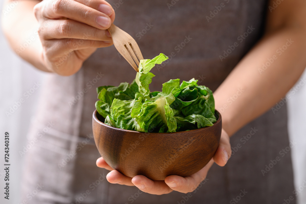 Organic cos romaine lettuce in wooden bowl holding by woman hand and eating, Food ingredient for healthy salad