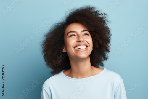 Portrait of a happy young african american woman laughing against blue background