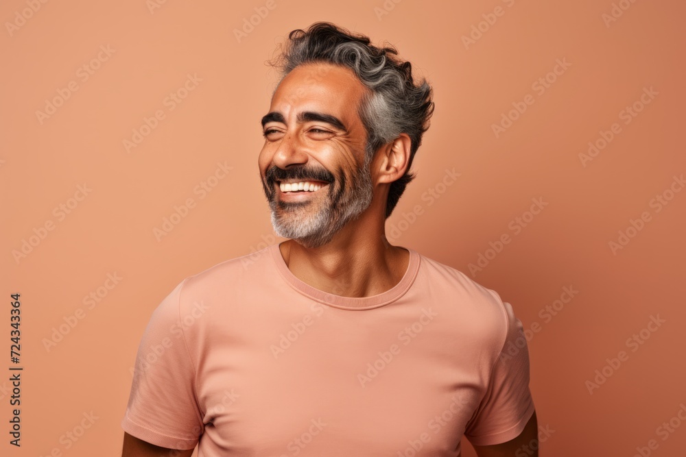 Portrait of happy mature Indian man in casual t-shirt, isolated on brown background Portrait of happy mature Indian man in casual t-shirt, isolated on brown background