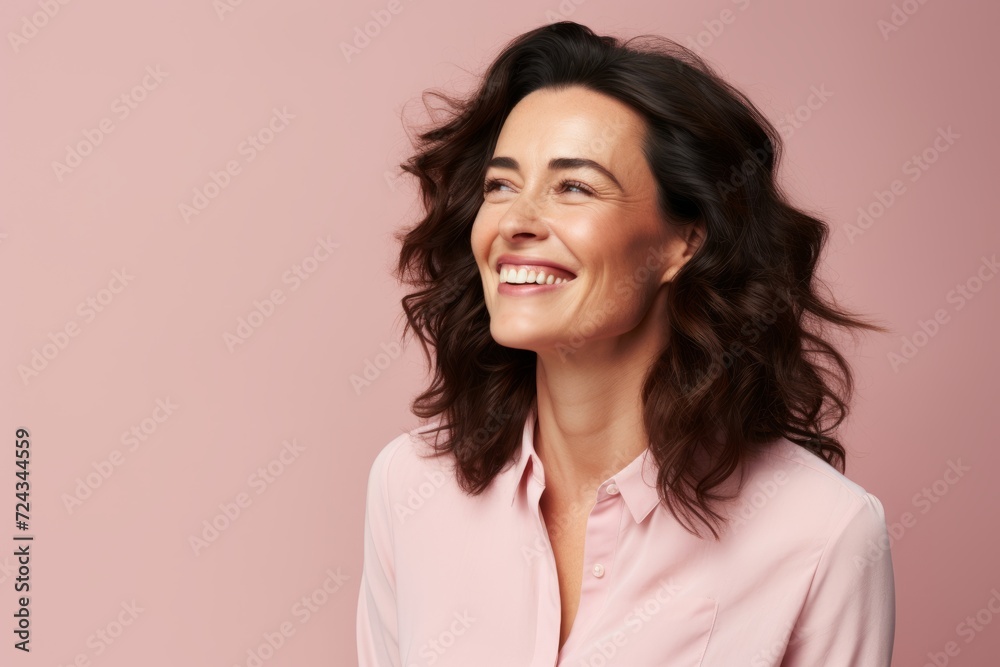 Portrait of a smiling middle aged woman looking away over pink background Portrait of a smiling middle aged woman looking away over pink background