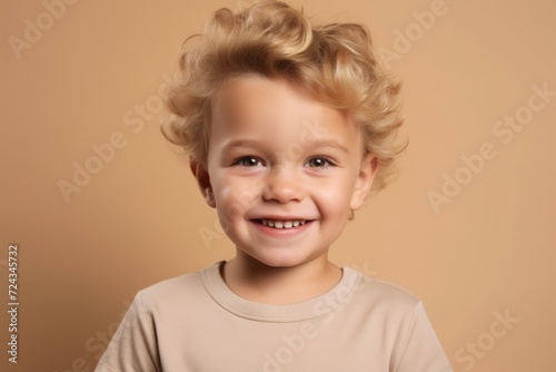 Portrait of a smiling little boy with blond hair on a beige background