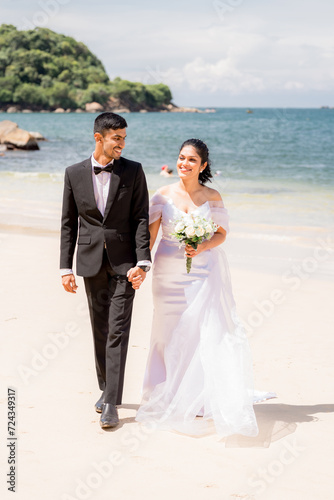 bride and groom on the beach, walking, smiling