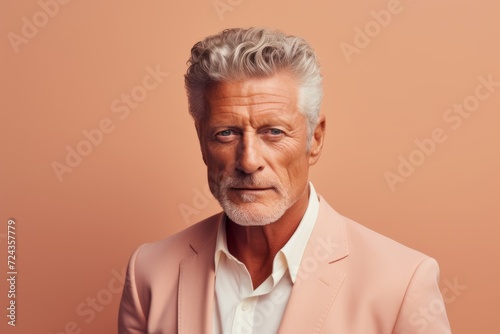 Portrait of a senior man with grey hair wearing a pink jacket.