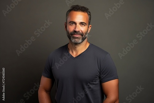Handsome middle-aged man with beard and mustache in a black t-shirt on a gray background