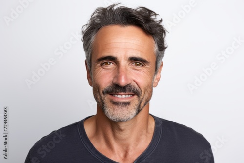 Handsome middle aged man with beard and mustache looking at camera while standing against grey background