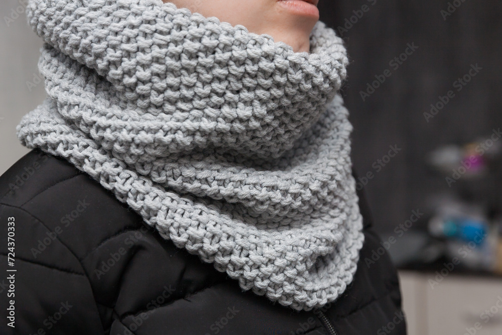 Hand made designed warm gray color knitted snood scarf on a girl's neck Hand made designed warm gray color knitted snood scarf on a girl's neck