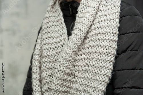Long gray handmade knitted textured snood scarf on a girl's neck close up