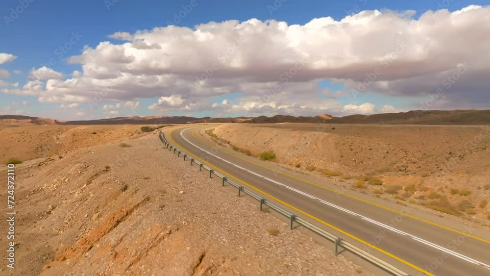 Empty Desert highway mountain road with Blue cloudy sky, slow camera movement pull back aerial view from the curve to above the lanes Empty Desert highway mountain road with Blue cloudy sky, slow camera movement pull back aerial view from the curve to above the lanes
