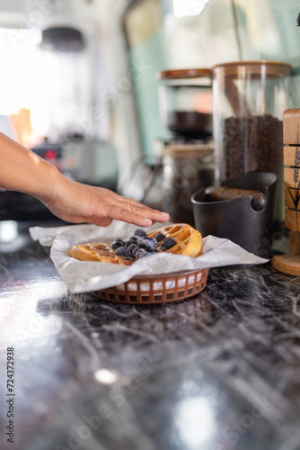 Worker garnishing a waffle with fresh berries