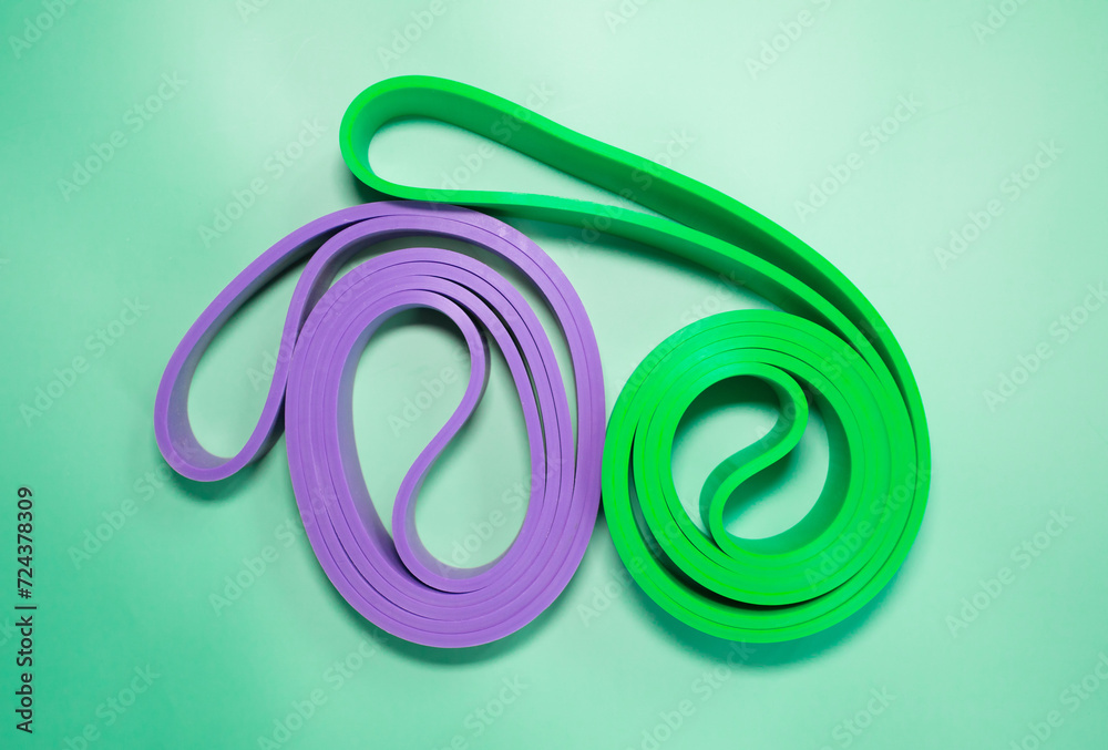 Fototapeta premium The concept of sports, fitness and a healthy lifestyle. Multicolored fitness rubber bands on a green background. Copy space .