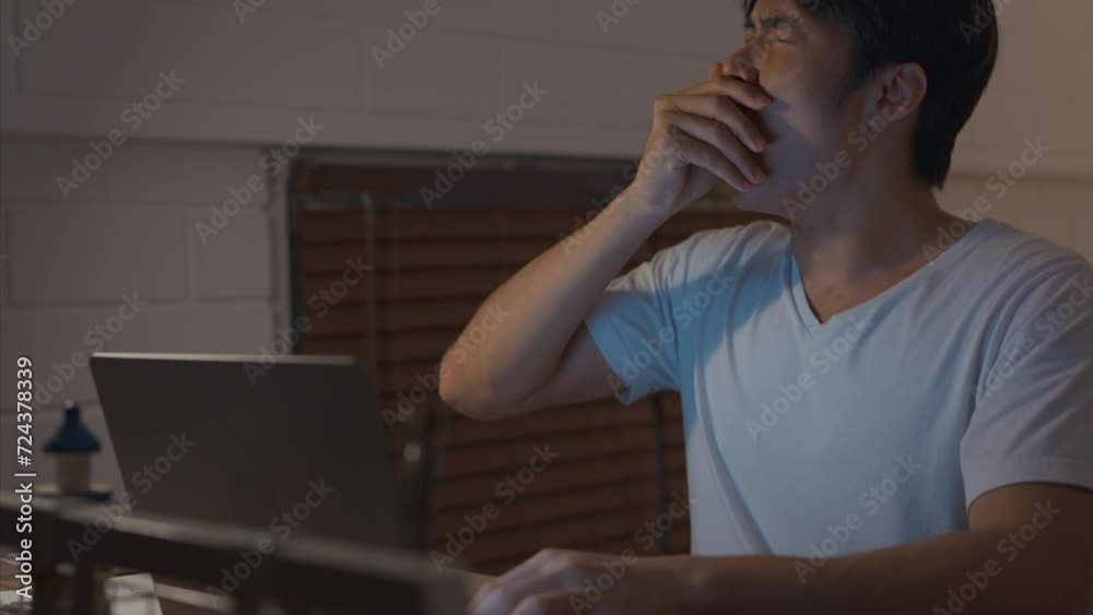 Asian depressed young man overworking alone on working table at night. 