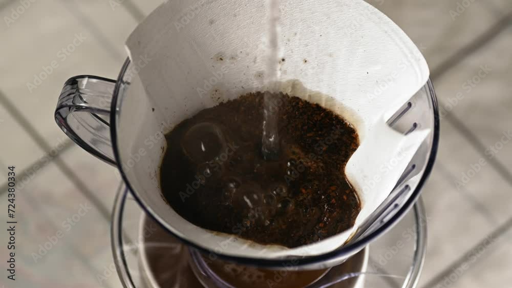 Pouring hot water into coffee beans and a filter supported by a coffee drip holder. Pouring hot water into coffee beans and a filter supported by a coffee drip holder.
