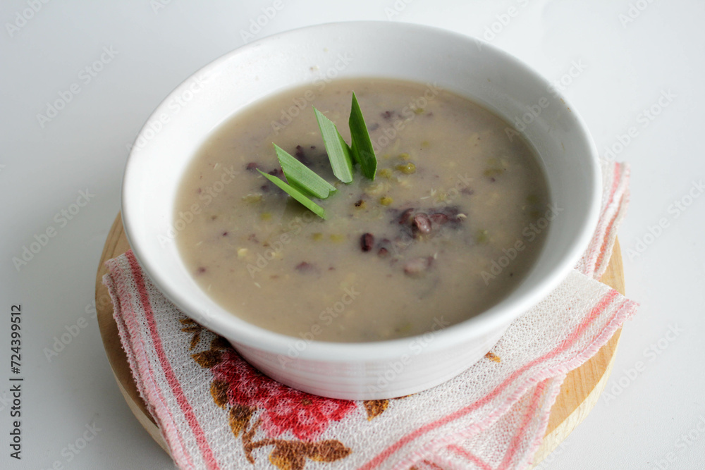 a close up of a bowl of green bean porridge and black sticky rice doused in coconut milk a close up of a bowl of green bean porridge and black sticky rice doused in coconut milk
