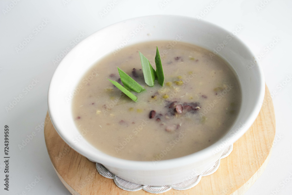 a close up of a bowl of green bean porridge and black sticky rice doused in coconut milk