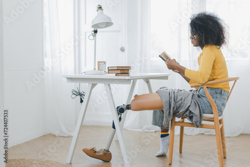 Woman with prosthetic leg sitting in chair in living room at home. Relaxed, happy woman at home living room sitting on the chair, using tablet