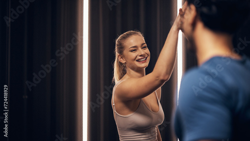 Smiling woman high-fiving her trainer after a gym workout photo