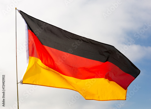 Black, red, and gold tricolor Bundesflagge, national symbol of idea of strong and united democratic Germany, culture and rich history waving on flagpole against backdrop of cloudy sky photo