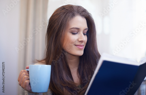 Woman, drinking coffee and reading book to relax at home, literature and fiction novel for knowledge. Female person, happy and information for learning, comfortable and fantasy story on weekend