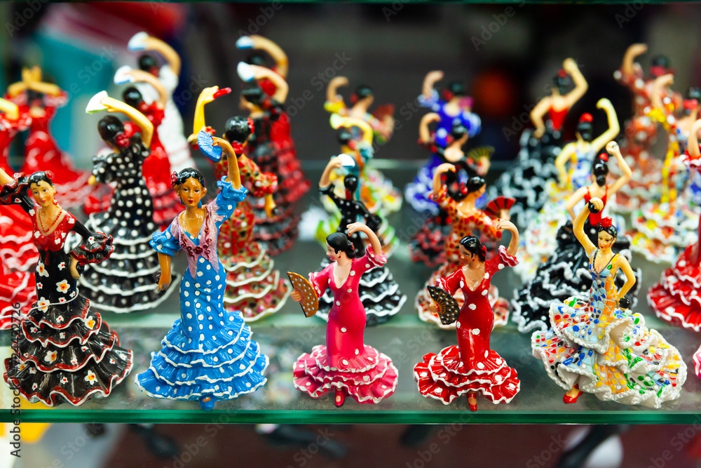 Ceramic mosaic and painted flamenco dancers figurines in colorful traditional dresses on showcase of Spanish souvenir shop..