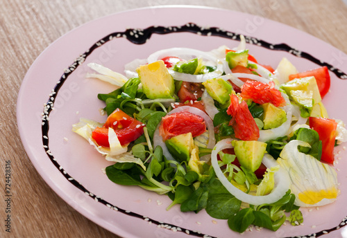 Vitamin salad from avocado, tomatoes, grapefruit and fresh cornsalad in white plate..