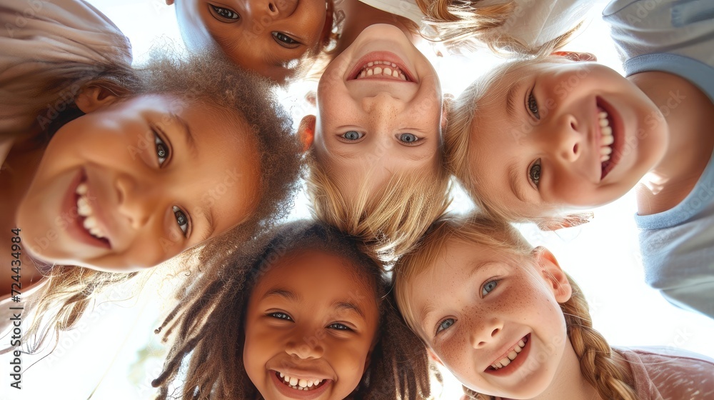 A group of children from diverse ethnic backgrounds looking down at the camera, smiling.