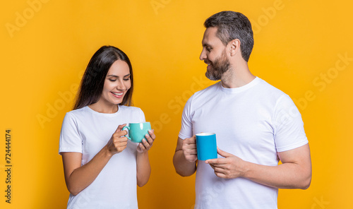 Couple of man and woman drinking tea. Family day together. Warm relationship. Coffee break at home. Family couple having coffee isolated on yellow. Morning coffee time. Deep conversation photo