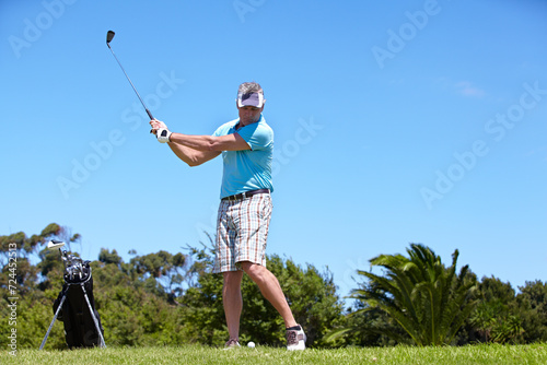 Senior, man and playing golf on green grass, lawn or field for sports, swing or taking a shot on course. Mature male person, golfer or player hitting ball or strike for goal, score or point in nature