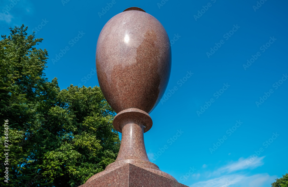 An ancient granite vase on a pedestal in the park.