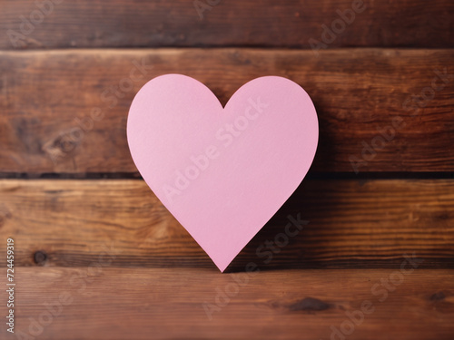 heart shape made of pink paper on wooden background with empty space in the middle for text