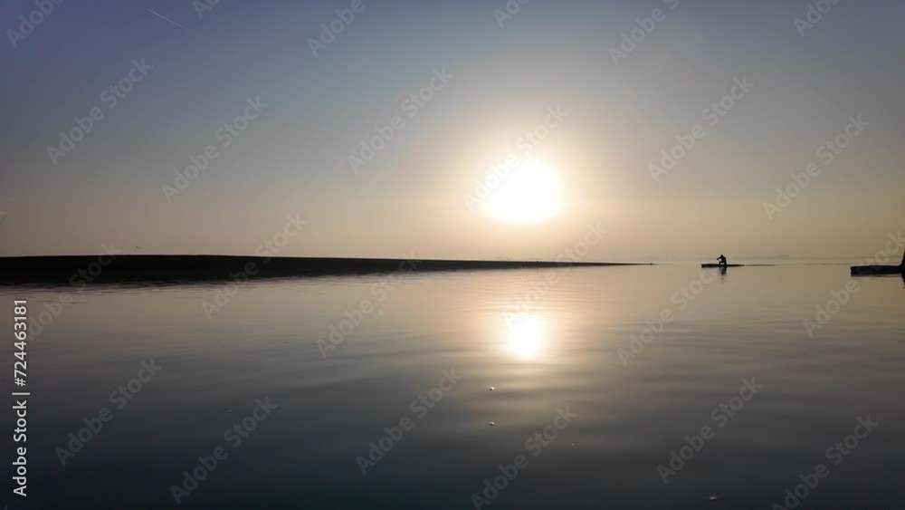 Serene Sunset Paddleboarding at a Calm Coastal Location.A tranquil scene of two people paddleboarding on still waters under the soft glow of a setting sun. Serene Sunset Paddleboarding at a Calm Coastal Location.A tranquil scene of two people paddleboarding on still waters under the soft glow of a setting sun.