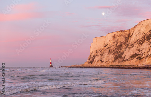 Sunrise and moonset at beachy head lighthouse during low tide east Sussex coast south east England UK