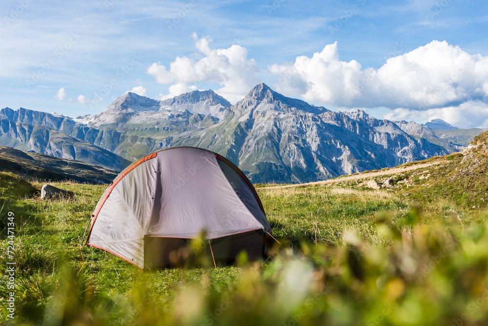 Pitched trekking tent on a pass in the Swiss Alps on a sunny summer day